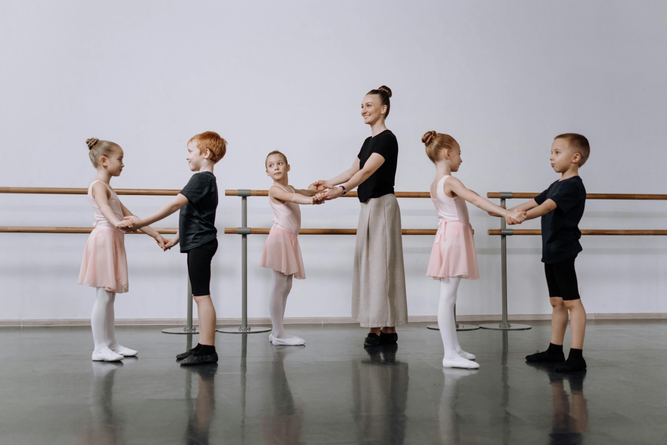 Instructor guides children in ballet class, focusing on dance basics.